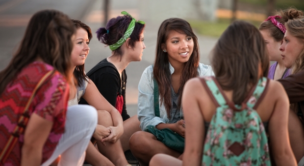 En grupp unga kvinnor sitter i grupp och pratar