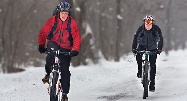 Två personer som cyklar på en vinterväg