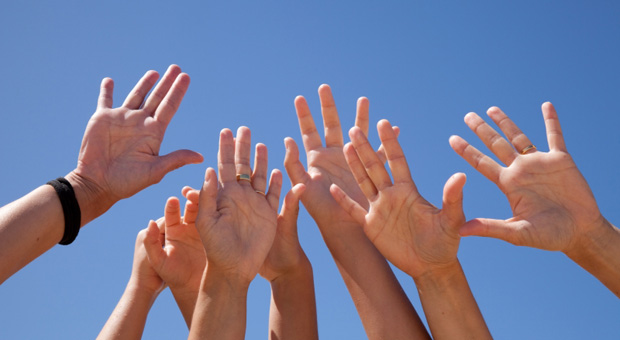 Foto på personer som räcker upp händerna i luften.