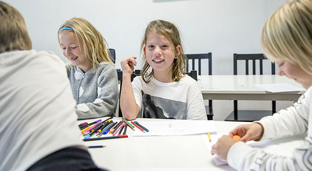 Flicka i klassrum som ler mot kameran.